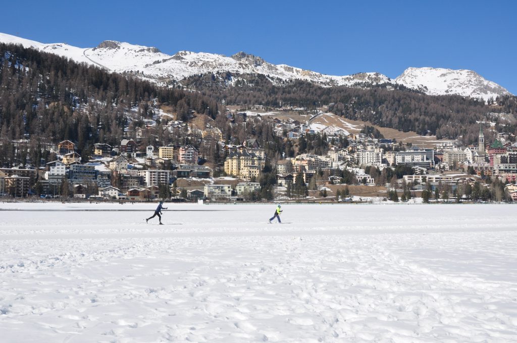 Zwei Langläufer auf dem zugefrorenen St. Moritz-See vor der Kulisse von St. Moritz.